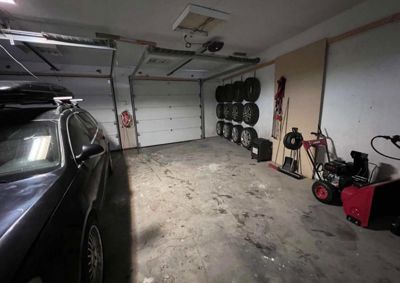 Fotografi av en garasje med en bil, dører og utstyr.