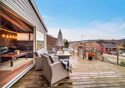 Fotografi av en terrasse med møbler og utsikt over et landskap.