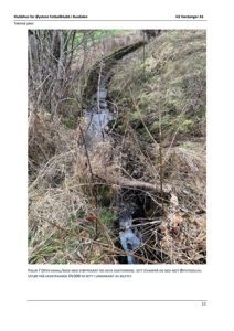 Fotografi av en åpen kanal/bekk med støyvekant og heva sideterreng, sett ovenfra og ned mot Øysteseelva.