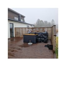 Fotografi av en ferdig eller nesten ferdig utlagt terrasse med en moderne villa i bakgrunnen.