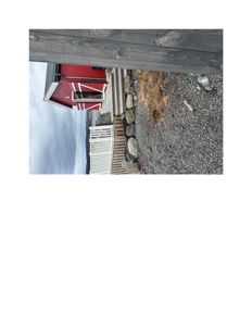 Fotografi av en rød bygning med trapp og steinmur sett fra siden.