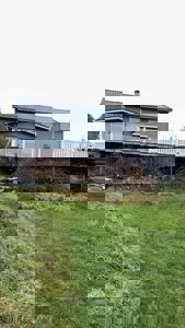 Fotografi av en grå hytte med en utvendig terrasse og en hage.