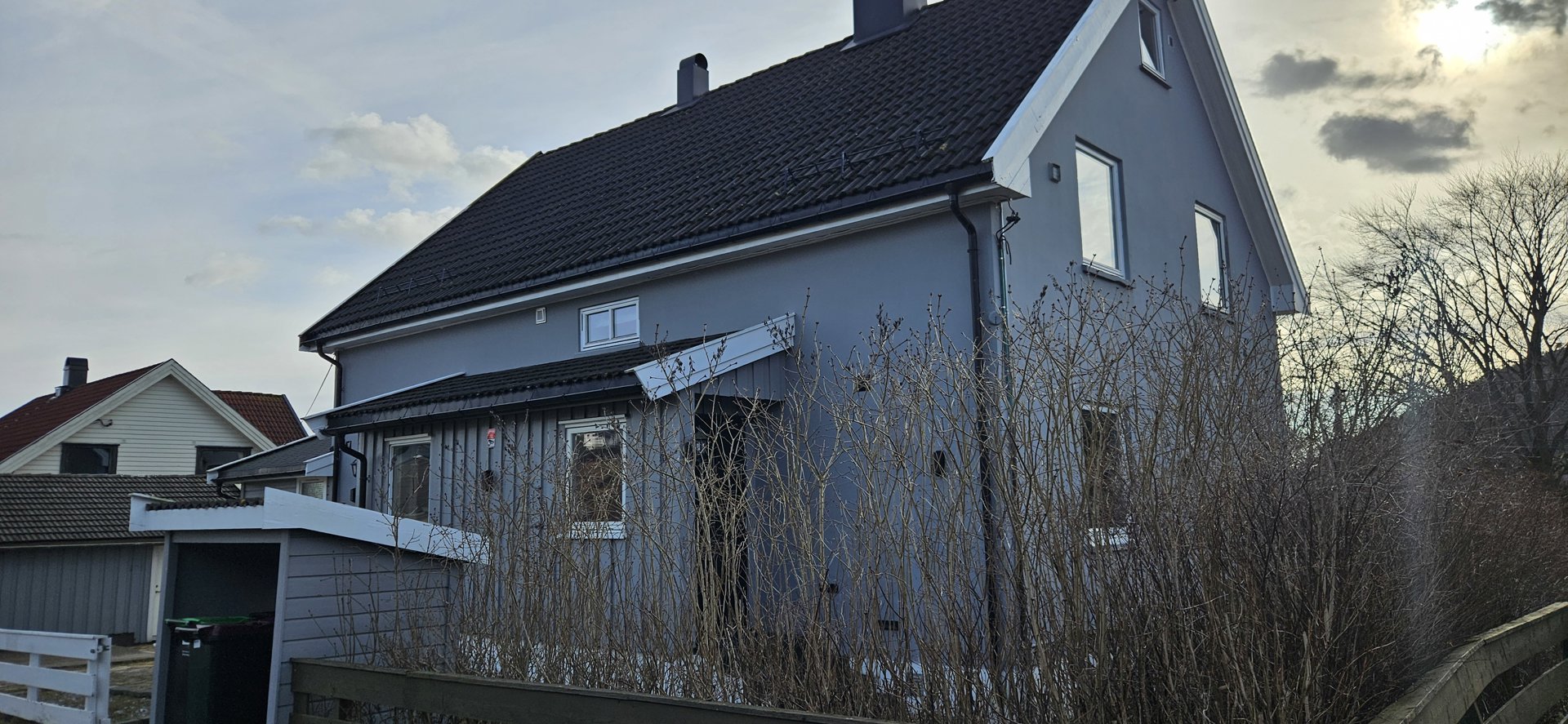 Fotografi av en grå fargefarget bolig sett fra siden.
