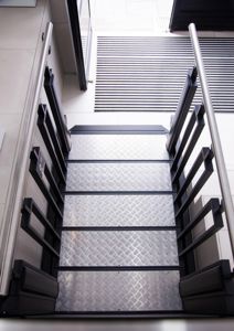 Fotografi av en metalltrapp med håndtak og gummistøtter.