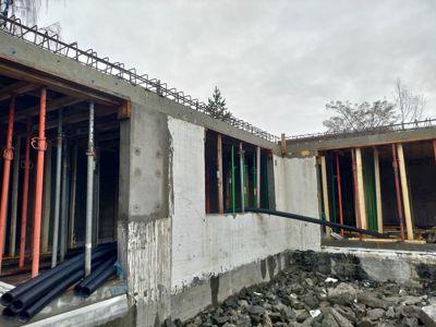 Fotografi av en byggeplass som viser en betongkonstruksjon i ferdigstillelse med stålskjelett og støtter.