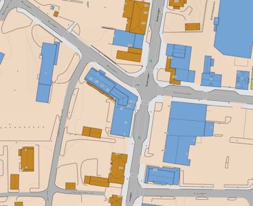 Kart som viser en bydel med gater (f.eks. Bruvegen, Stasjonsvegen) og bygninger markert med farger.