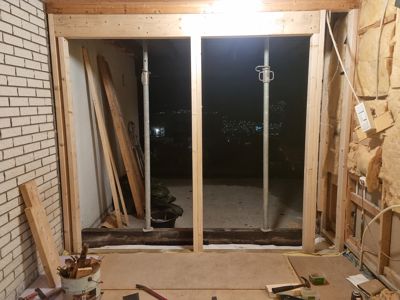 Fotografi av en byggeplass som viser en ny installert døråpning med ramme og støtter.