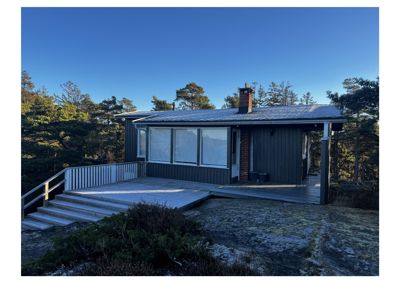 Fotografi av en enebolig sett fra siden, med omgivende natur og terrasser.