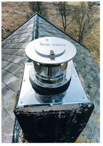 Fotografi av en metallisk røykpipe (merket 'ROYKØR REHABPIPE') på et tak.