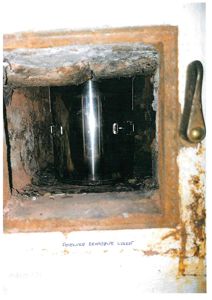 Fotografi av en feiluke med en lukket reabsøppning (rehabpipe) sett innvendig.