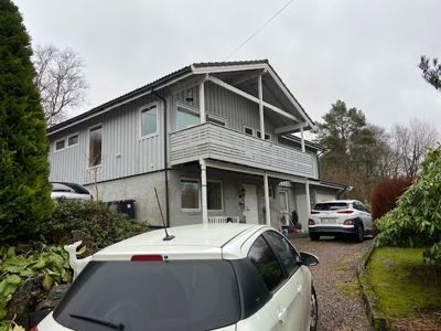 Fotografi av en eksisterende toetasjes bolig sett fra siden, med bil i forgrunnen.