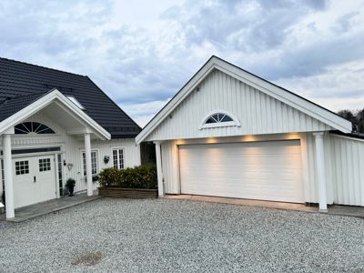 Fotografi av en hvit villa med garasje sett fra foran.