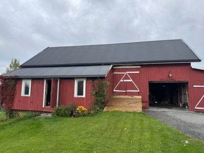 Fotografi av en rød skurbygning med grå tak, sett fra front.