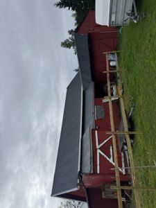 Fotografi av en rød skurbygning med mørk takbekledning, sett fra siden.