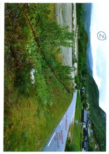 Fotografi av en eksisterende vei og skråning med håndtegnede merkelinjer og tekst som indikerer grenser eller eksisterende grøft.