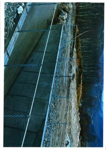 Fotografi av en betongkonstruksjon (kanskje en bro eller en vegg) med en hekk foran, sett fra en høyde.