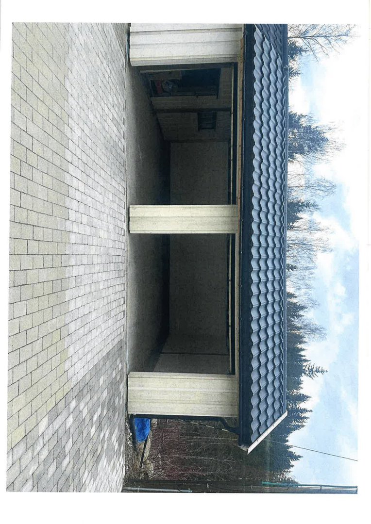 Fotografi av en ferdig eller nesten ferdig bygning sett fra siden, med en betongtårnvegg og et tak.