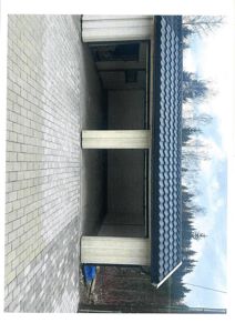 Fotografi av en ferdig eller nesten ferdig bygning sett fra siden, med en betongtårnvegg og et tak.