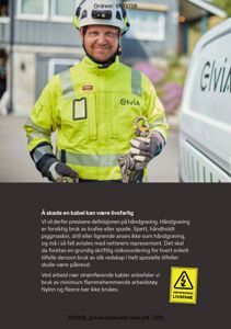 Fotografi av en person i sikkerhetsutstyr (helmet, reflekterende jakke, hansker) som holder en kabel. Bakgrunnen viser en bygning og en bil. Bildet illustrerer sikkerhetsrutiner ved håndgraving.