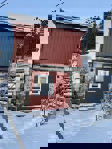 Fotografi av en rød og steinlagt bygning med snø på taket og trapp.