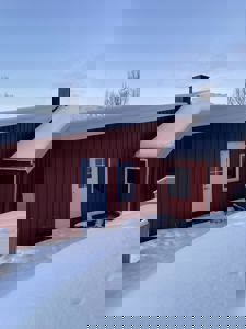 Fotografi av en rød bygning med snø på taket og bakken.