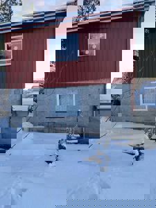 Fotografi av en rød og grå bygning sett fra siden, med snø på bakken og taket.