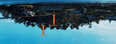 Fotografi av et kystnabolag med hus på en skråning, med overlagte oransje piler og tekst som peker på 'Vegbane' og 'Tilbygg'.