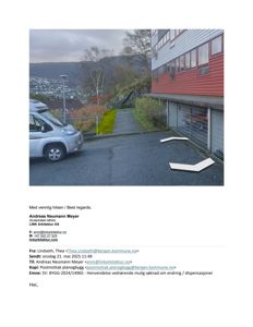 Fotografi av en bygning med en bil og en vei i forgrunnen, med en by i bakgrunnen.