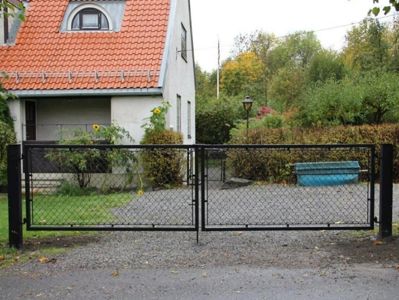 Fotografi av en bolig med gateport, hage og omgivelser.