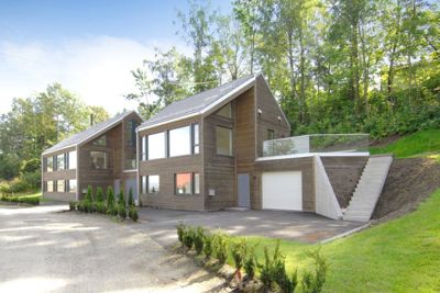 Fotografi av en moderne trehus med garasje og trapp opp til en terrasse, sett fra bakkenivå.