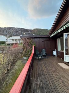 Fotografi av en terrasse med utsikt over nabohus og fjell.