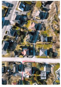 Flyfoto av et boligområde med en markert eiendom (rødt område) og en vei.