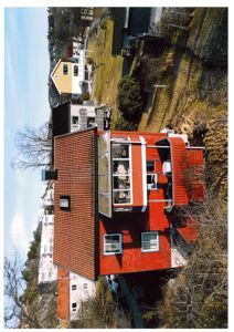 Fotografi av en rød fargegitt bygning sett fra lufta, med naboer i bakgrunnen.