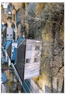 Luftfoto av en hvit bygning med mørk takbeplating, sett fra en høy vinkel.