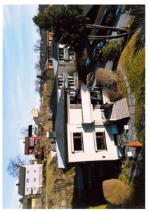 Fotografi av en eksisterende bolig sett fra siden, med naboer og omgivende terreng.