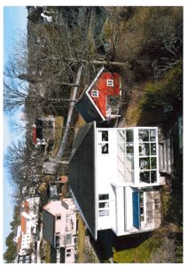 Fotografi av en hvit villa med et glassveranda, sett fra lufta eller en høy vinkel, med naboer i bakgrunnen.
