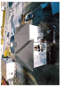 Luftfoto av en bolig sett fra høyre side, med nærliggende hus og gatelys.