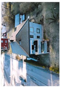 Luftfoto av en bolig sett fra høyden, som viser bygningens plassering i forhold til vei og naboer.