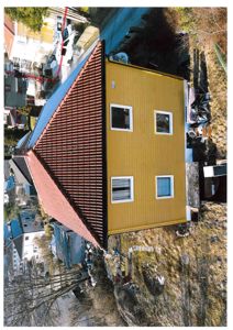 Fotografi av en gul ferdigbygd husfasade sett fra en høy vinkel.