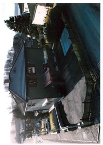 Fotografi av en eksisterende bolig sett fra en vinkel som viser både fasade og deler av tomten.