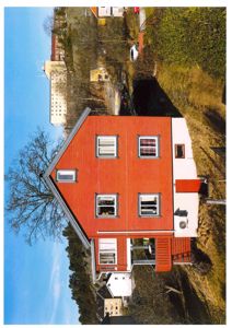 Fotografi av en rød trehus med hvit sidevegg, sett fra siden.