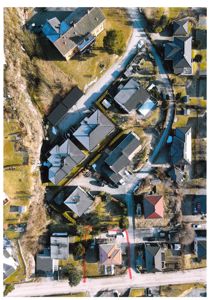 Luftfoto av et boligområde med flere hus, veier og grøntområder. Bildet viser nabolagsoversikt.