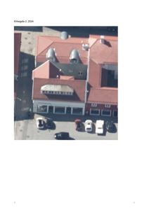 Luftfoto av en bygning med rødt tak og parkeringsplass foran.