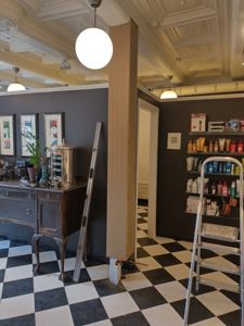 Fotografi av et interiør med sjakkfliser, mørke vegger, dekorativt tak og innredning.