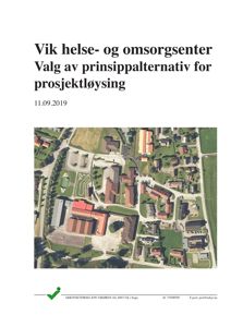 Flyfoto av et eksisterende område med flere bygninger, parkeringsplasser og veier.