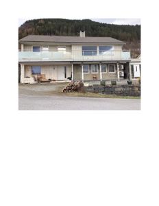 Fotografi av en toetasjes bolig med balkong, sett fra gaten mot bakken.