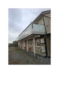 Fotografi av en bygning sett fra siden, som viser fasade, etasjeplan med balkong, og omgivelsene.