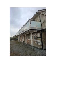 Fotografi av en bygning sett fra siden, som viser fasade, balkong og utvendige enheter.