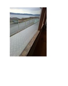 Fotografi av et balkongområde med utsikt over vann og fjell.