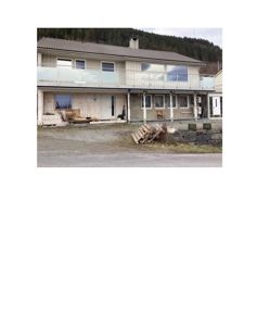 Fotografi av en toetasjes bolig under eller etter utvendig rehabilitering, med palletter og byggematerialer foran.